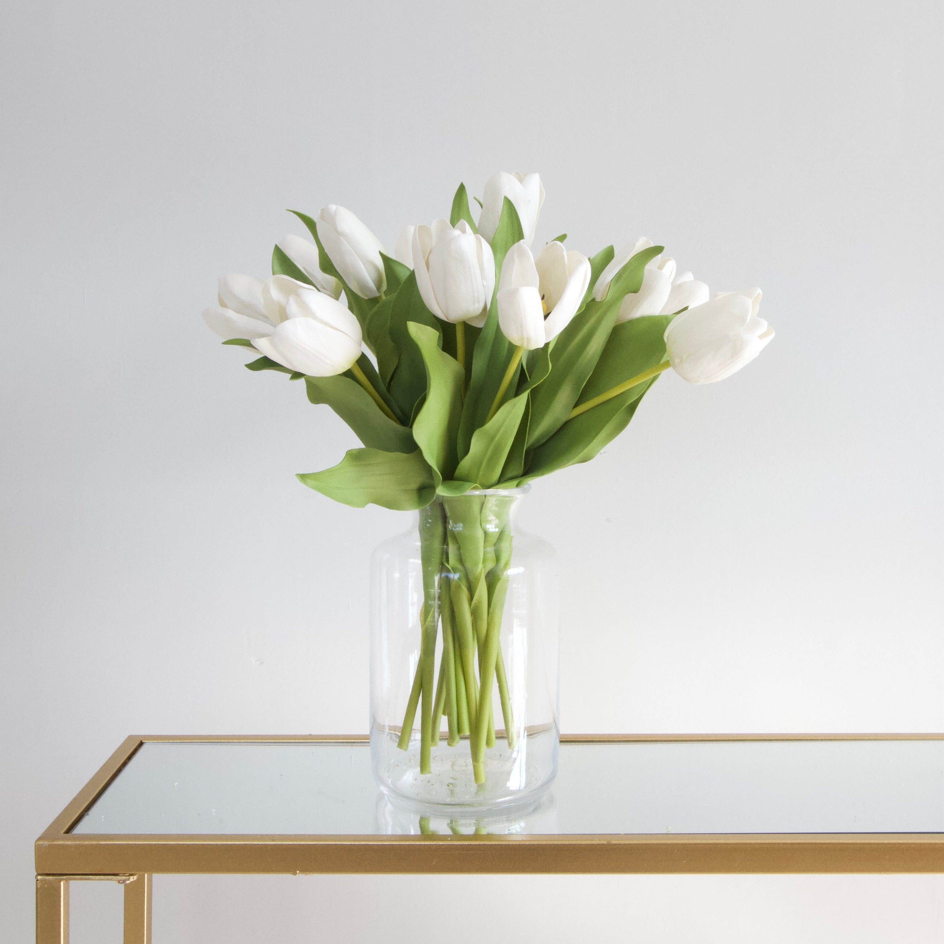 Luxury Lifelike Realistic Artificial Fabric Silk Blooms with Foliage Buy Online from The Faux Flower Company | 12 stems of Short Open White Tulip ABY2618WH styled in Clear Glass Medium Funnel Neck Vase ABV2252
