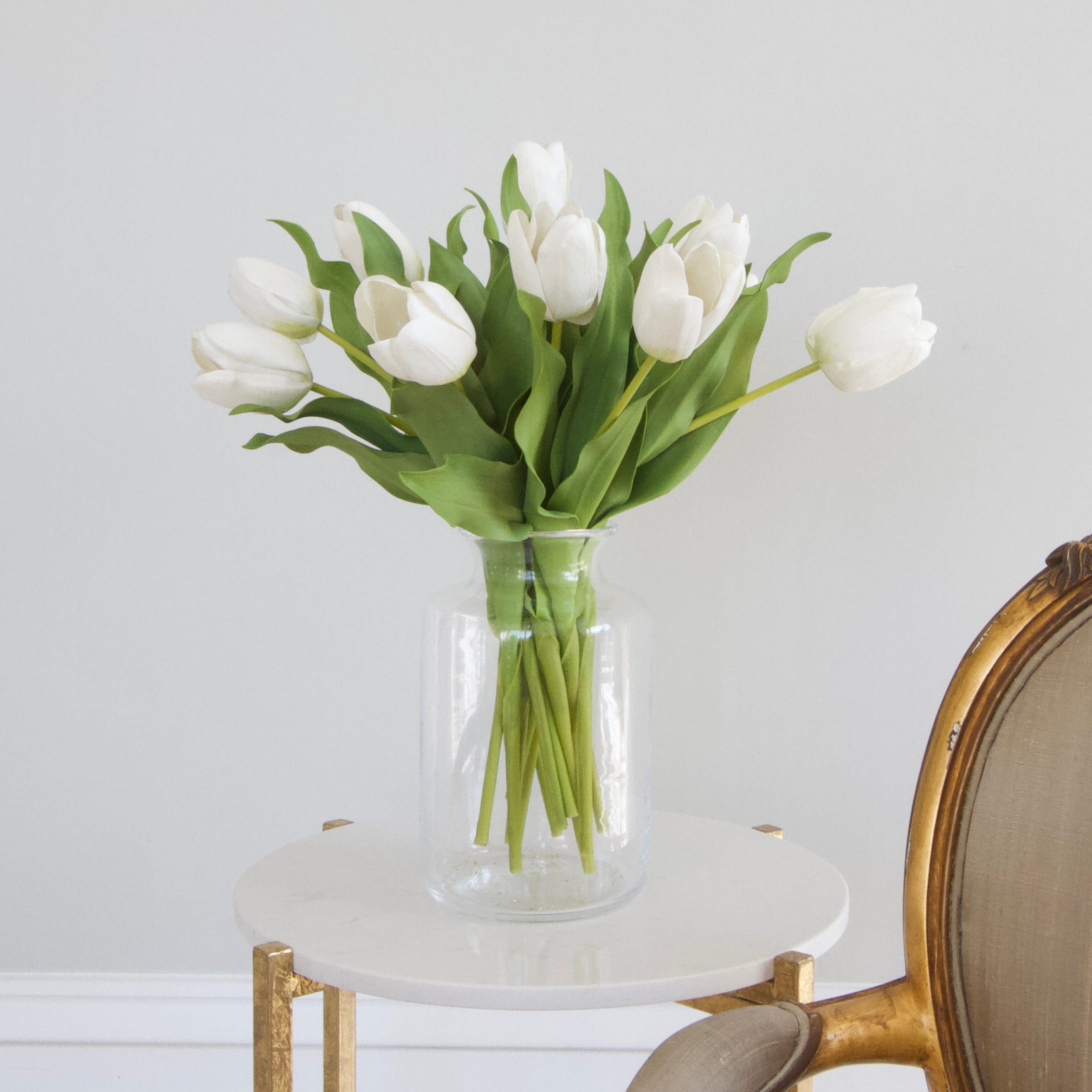 Luxury Lifelike Realistic Artificial Fabric Silk Blooms with Foliage Buy Online from The Faux Flower Company | 12 stems of Short Open White Tulip ABY2618WH styled in Clear Glass Medium Funnel Neck Vase ABV2252
