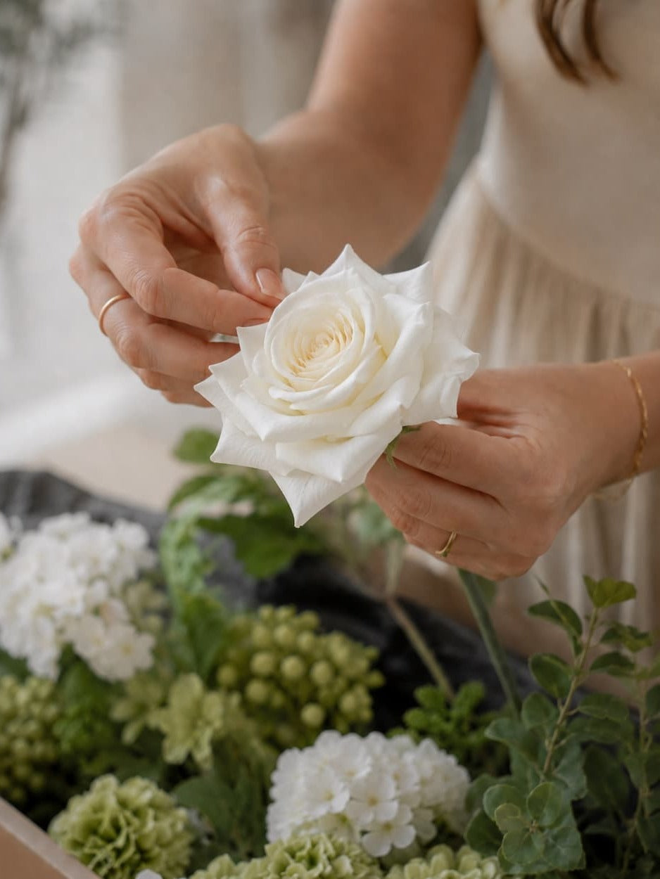 Gently opening the outer petals of a white faux rose