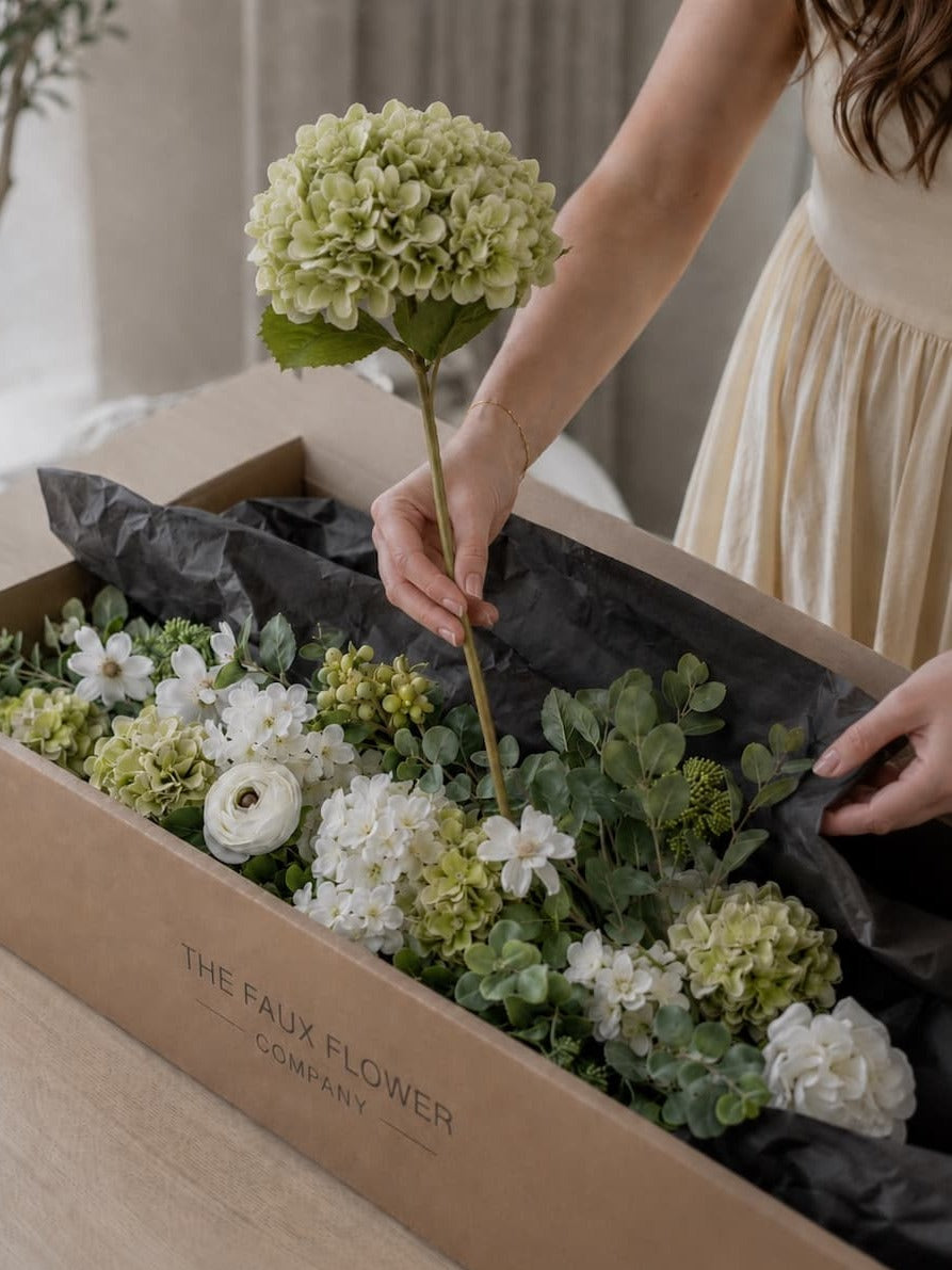 Lifting faux flowers from their packaging by the stems